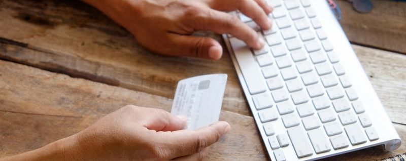 person typing credit card details via keyboard - SingSaver